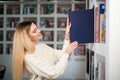 Woman taking book from library bookshelf. Young librarian searching books and taking one book from library bookshelf. Royalty Free Stock Photo