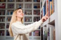 Woman taking book from library bookshelf. Young librarian searching books and taking one book from library bookshelf. Royalty Free Stock Photo