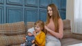 Woman taking care, brushing hair of her sister child girl in living room, kid playing with toy doll Royalty Free Stock Photo