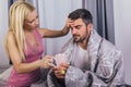 Woman taking care of her sick boyfriend at home Royalty Free Stock Photo