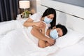 Woman taking care of her sick husband on bed at home, couple wearing medical mask for protection coronavirus covid-19 pandemic Royalty Free Stock Photo