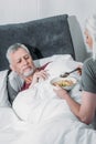 Woman taking care of sick husband in bed at home Royalty Free Stock Photo