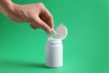 Woman taking chewing gums from jar on green background, closeup