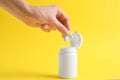 Woman taking chewing gums from jar on yellow background, closeup