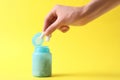 Woman taking chewing gums from jar on yellow background, closeup