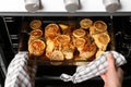 Woman taking delicious lemon chicken out of oven Royalty Free Stock Photo