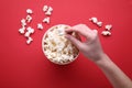 Woman taking delicious popcorn from paper bucket on red background, top view Royalty Free Stock Photo