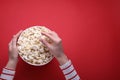 Woman taking delicious popcorn from paper bucket on red background, top view. Space for text Royalty Free Stock Photo