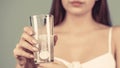 Woman taking drugs to releave headache. Woman take some pills, holds glass of water. Young woman taking pill against