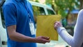 Woman taking envelope with documents from deliverer hands, door-to-door shipment