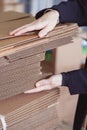 Woman taking folded stacks of corrugated cardboards for packing in warehouse Royalty Free Stock Photo