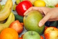 A woman taking a mango out of a pile of fruit and vegetables Royalty Free Stock Photo