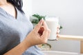 Woman taking medicine with glass of milk and paracetamol pill in hand