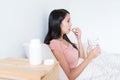 Woman taking medicine and holding glass of water on bed Royalty Free Stock Photo