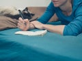 Woman taking notes in bed with cat Royalty Free Stock Photo