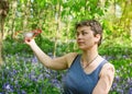 Woman  taking off her mask and sitting on meadow between bluebells in forest Royalty Free Stock Photo