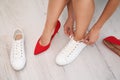 Woman taking off uncomfortable shoes and putting on sneakers in office, closeup. Tired feet after wearing high heels Royalty Free Stock Photo