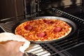 Woman taking out ready pizza out of the oven