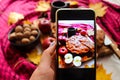 Woman taking photo of apple pie on mobile phone. Autumn atmosphere, mood. Selective focus, unfocused background