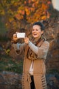 Woman taking photo with cell phone in autumn outdoors in evening Royalty Free Stock Photo