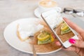 Woman taking photo of her cake in cafe with mobile phone Royalty Free Stock Photo