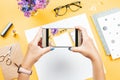 Woman taking photo of her office desk. Note books, accessories, stationery, flowers on table top, woman workspace, top view Royalty Free Stock Photo