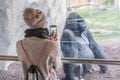 Woman taking photo of a huge silverback gorilla male behind glass in Biopark zoo in Valencia, Spain