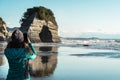 Woman taking a photo with mobile in what used to be Elephant Rock in New Plymouth, New Zealand