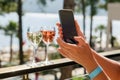 A woman is taking photo of vine glasses by mobile phone