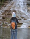 woman taking a photo of a waterfall in autumn with changing leaves on her mobile phone from behind Royalty Free Stock Photo