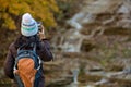 woman taking a photo of a waterfall in autumn with changing leaves on her mobile phone from behind Royalty Free Stock Photo