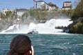 Woman taking photograph of Rhine Falls, most powerful waterfall in Europe.
