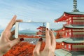 Woman taking photograph with a smart phone camera at Mt. Fuji with fall colors in Japan.