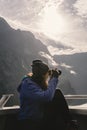Woman taking photos with camera on a cruise on Milford Sound. Fiordland National Park, New Zealand