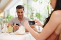 Romantic memories. A woman taking a picture while dining out with her partner at a restaurant. Royalty Free Stock Photo