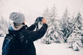 Woman taking a picture with her smartphone of the beautiful winter landscape in the mountains Royalty Free Stock Photo