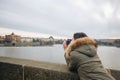 Woman is taking pictures on the Charles bridge in Prague. Young beautiful girl tourist stands on the Charles Bridge in Prague in Royalty Free Stock Photo