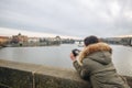 Woman is taking pictures on the Charles bridge in Prague. Young beautiful girl tourist stands on the Charles Bridge in Prague in Royalty Free Stock Photo