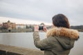 Woman is taking pictures on the Charles bridge in Prague. Young beautiful girl tourist stands on the Charles Bridge in Prague in Royalty Free Stock Photo