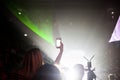 woman taking pictures at an event with a smartphone against green neon lights