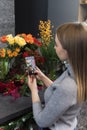 Woman taking pictures of flowers by her smartphone. The girl photographs the flowers that her lover gave her. A florist