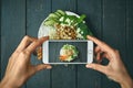 Woman taking pictures phobuddha bowl with vegan food, fried chickpeas, rice noodles with wegetables