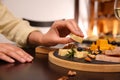 Woman taking piece of delicious cheese at table indoors Royalty Free Stock Photo