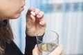 A woman is taking a pill. Females hands are holding one tablet and glass of water close up. Medicine and healthcare concept