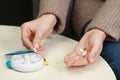 Woman taking pill from plastic container at white table, closeup Royalty Free Stock Photo