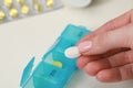 Woman taking pill from plastic container at white table, closeup Royalty Free Stock Photo