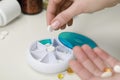 Woman taking pill from plastic container at white table, closeup Royalty Free Stock Photo