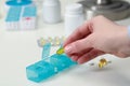 Woman taking pill from plastic container at white table, closeup Royalty Free Stock Photo