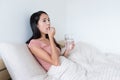 Woman taking pills and drink of water on bed Royalty Free Stock Photo