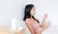 Woman taking pills and holding glass of water on bed Royalty Free Stock Photo